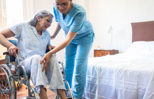 A nurse helping a woman out of here wheelchair